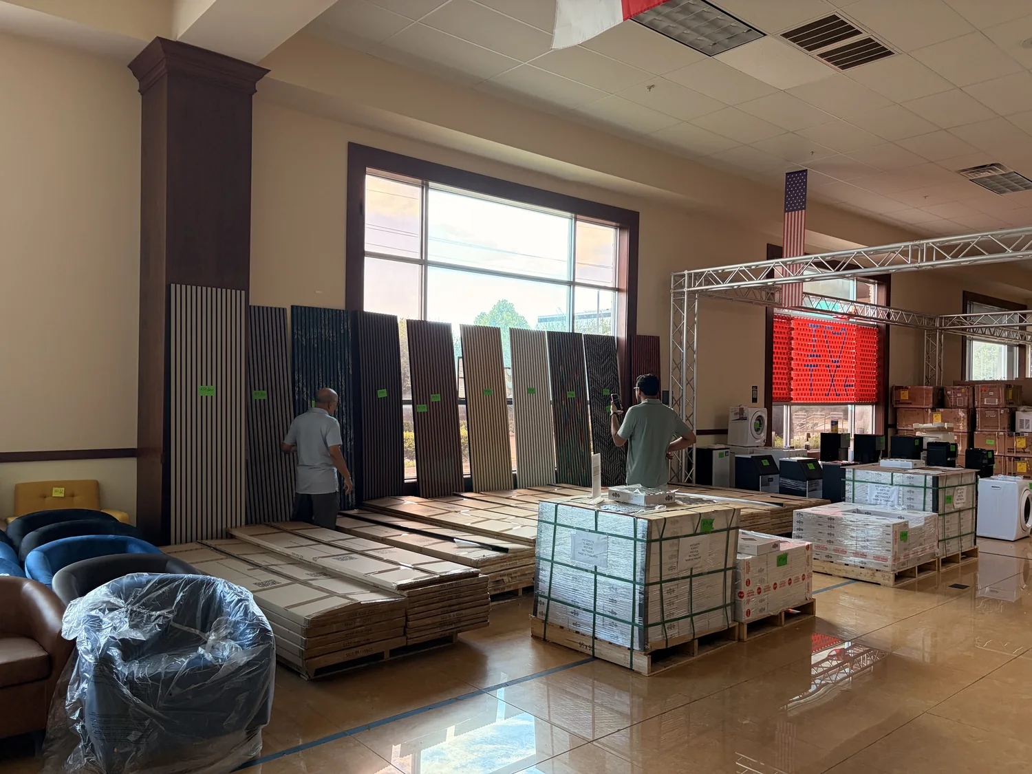 Acoustic slat wall panels stood up along the wall with pallets of boxed tile on the Cube-Age Houston sale floor