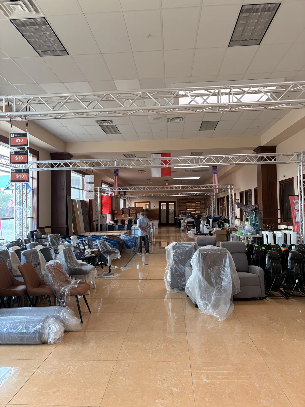 Cube-Age Houston sale floor with hanging ten dollar each signs above rows of chairs, recliners and drum fans