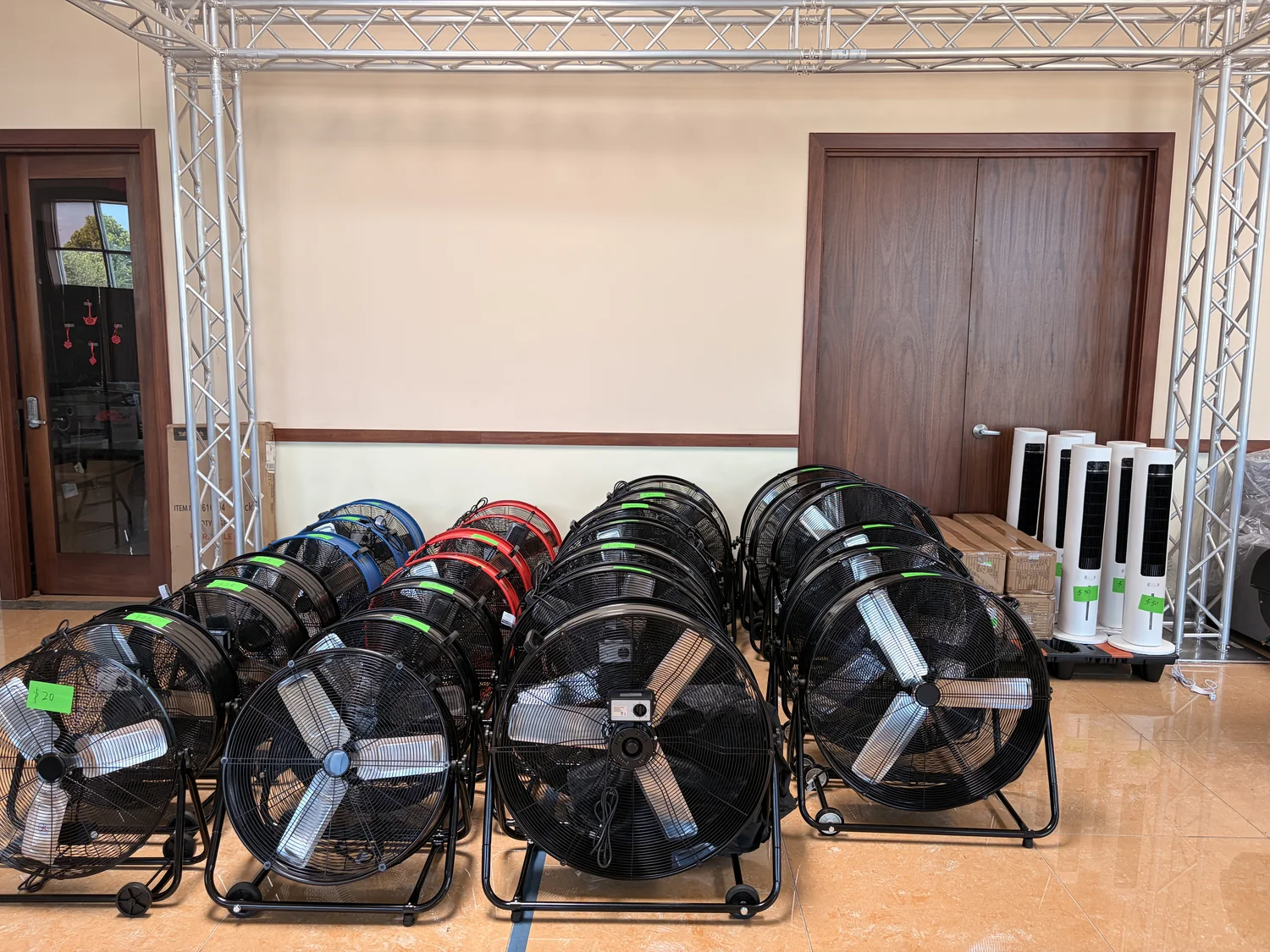 Rows of black drum fans with green price tags and white tower fans grouped together on the Cube-Age Houston sale floor