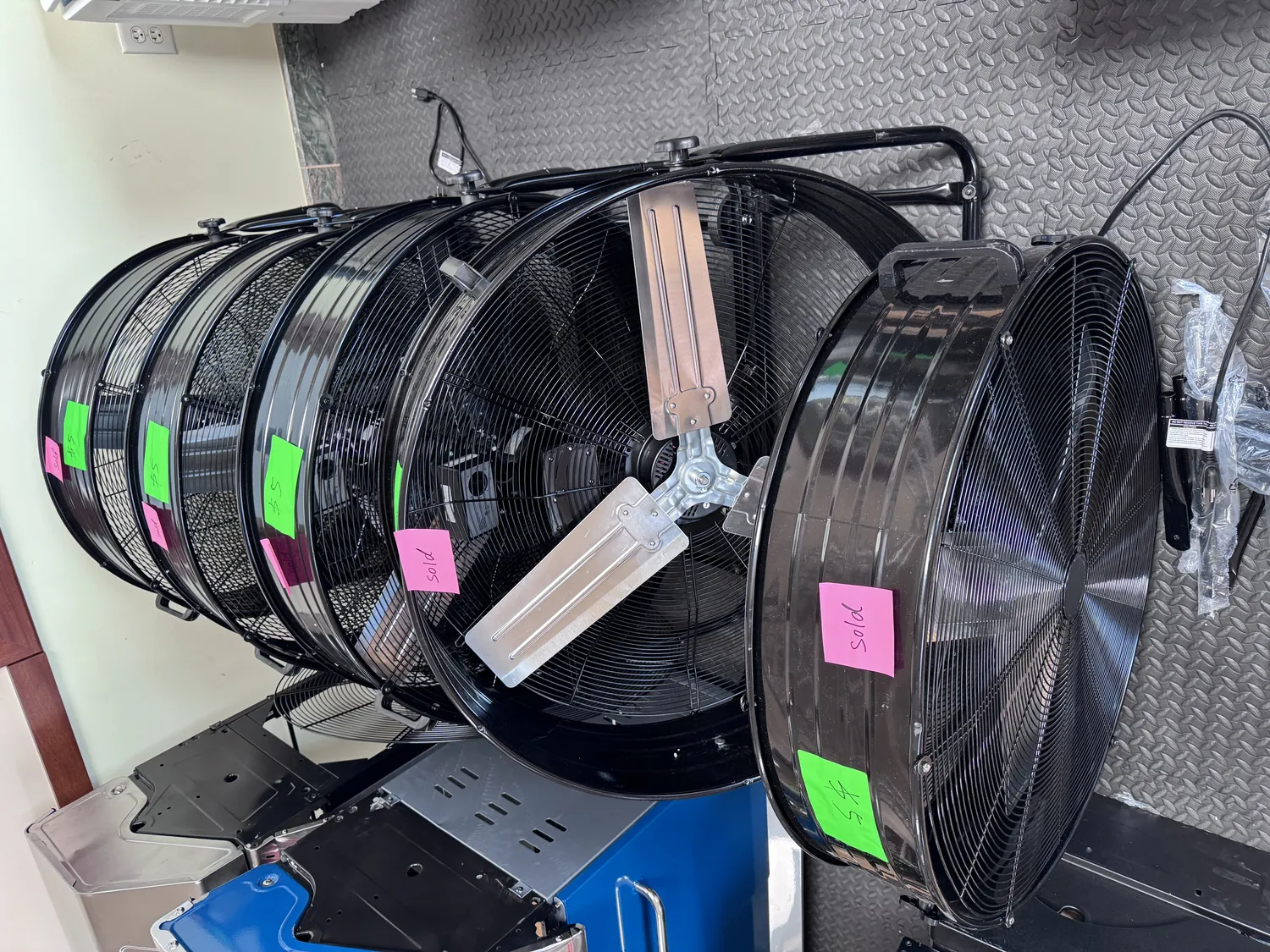 Row of high-velocity floor fans at the Cube-Age Houston warehouse, several tagged sold