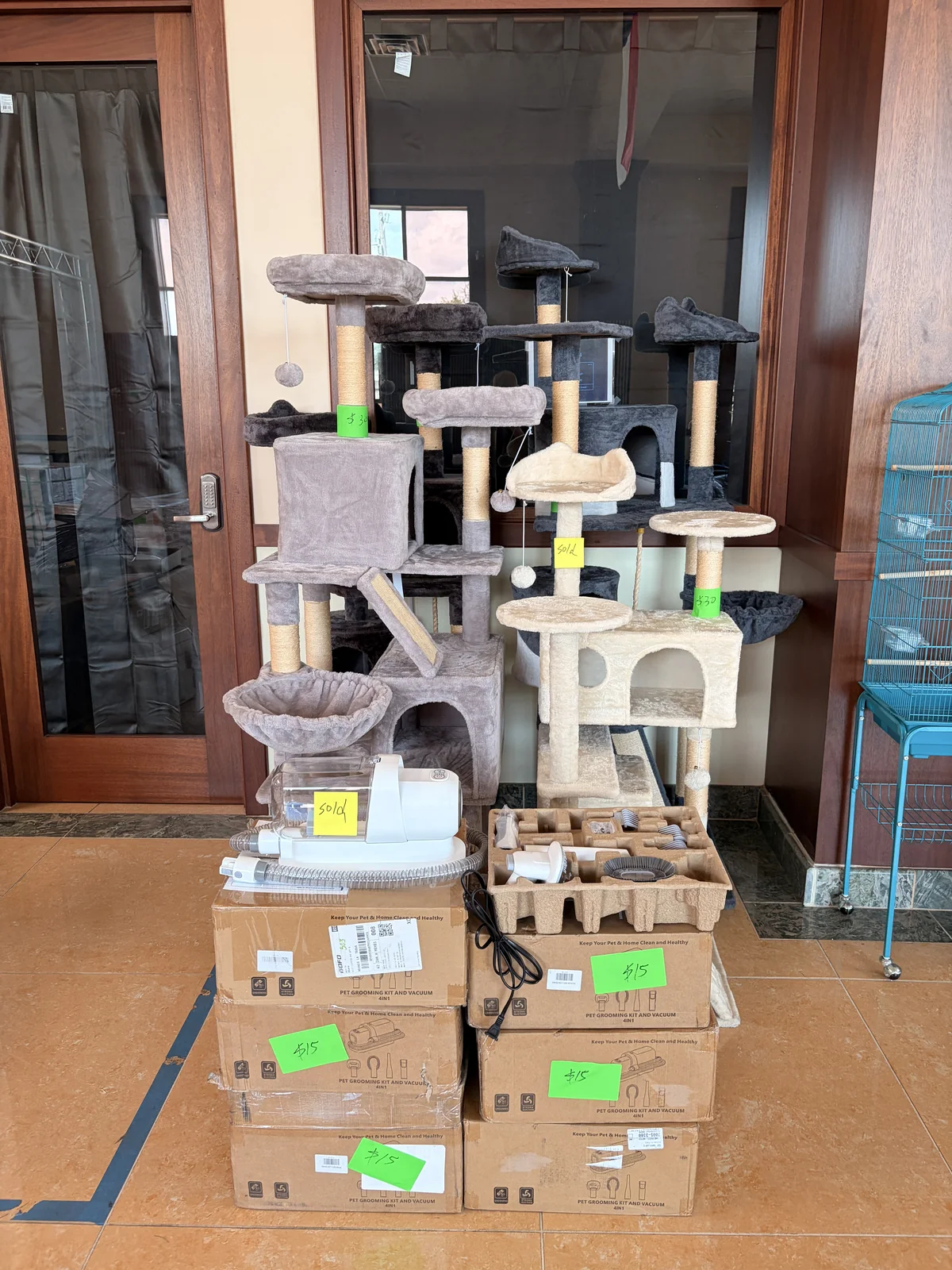 Cat trees and boxed pet grooming kits with handwritten price tags at the Cube-Age pop-up sale