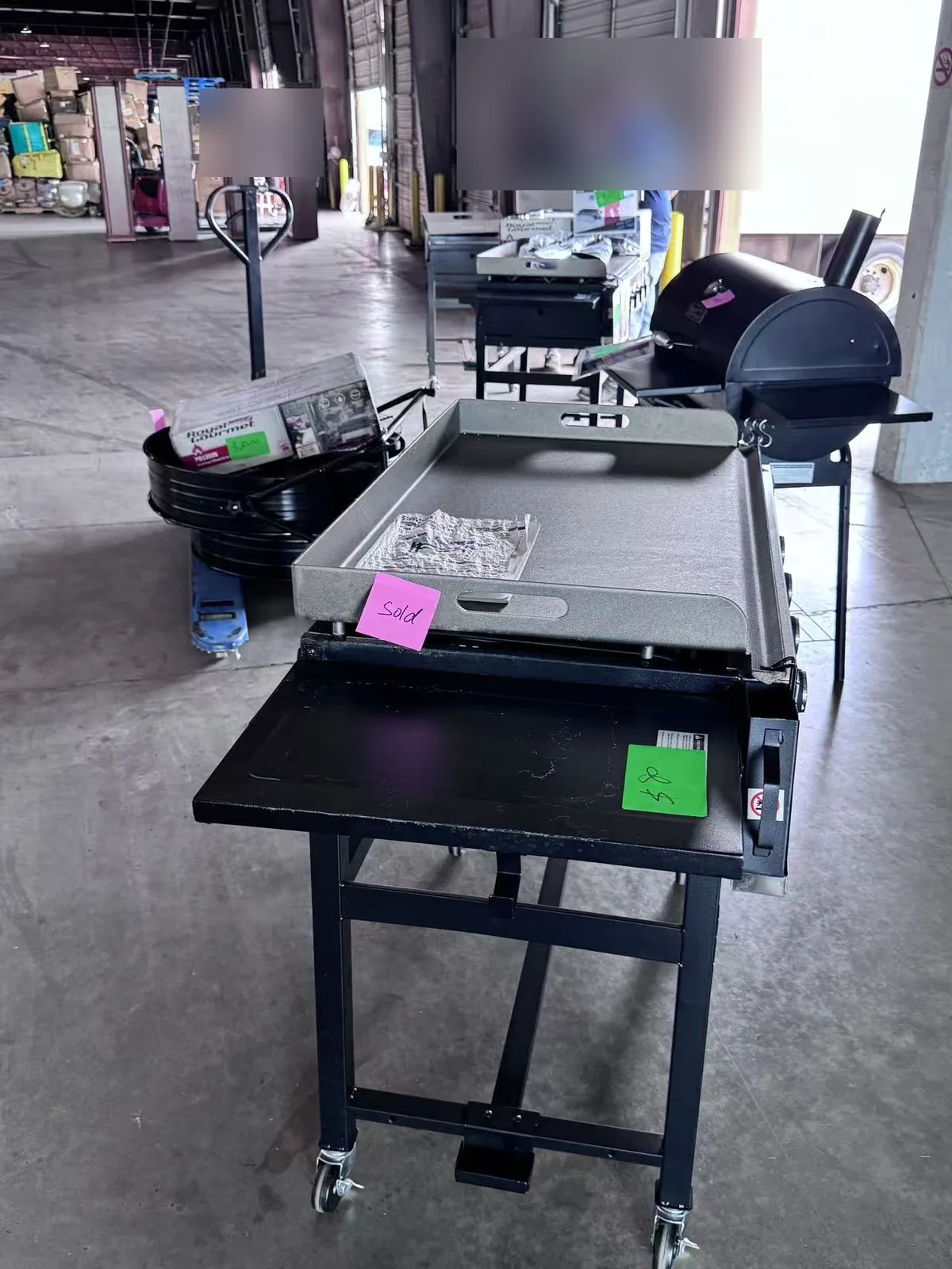 Griddles and smokers on the Cube-Age warehouse floor with sold tags