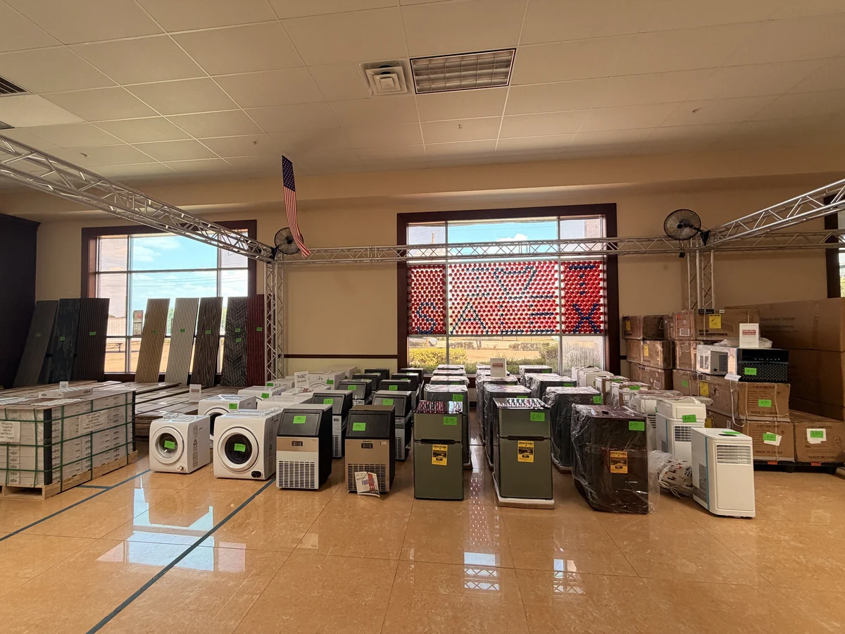 The small-appliance zone on the Cube-Age Houston sale floor, laundry, portable air conditioners and air coolers set out and price-tagged