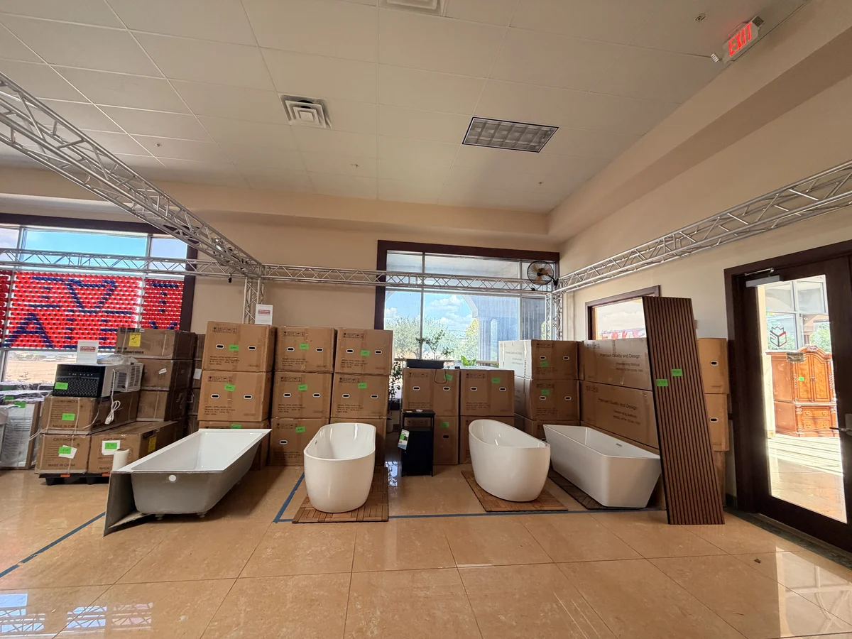 Freestanding bathtubs set out on the Cube-Age Houston sale floor with boxed stock behind