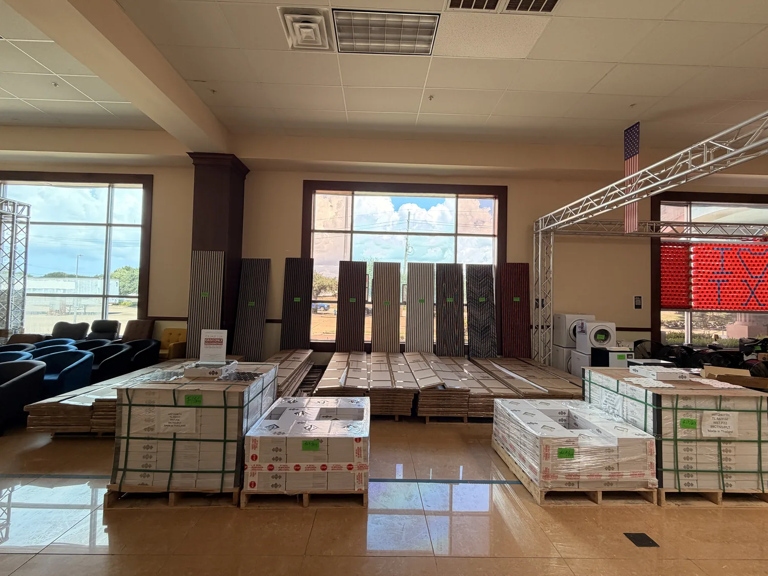 Acoustic slat panels stood up and pallets of boxed hexagon tile newly staged on the Cube-Age Houston sale floor