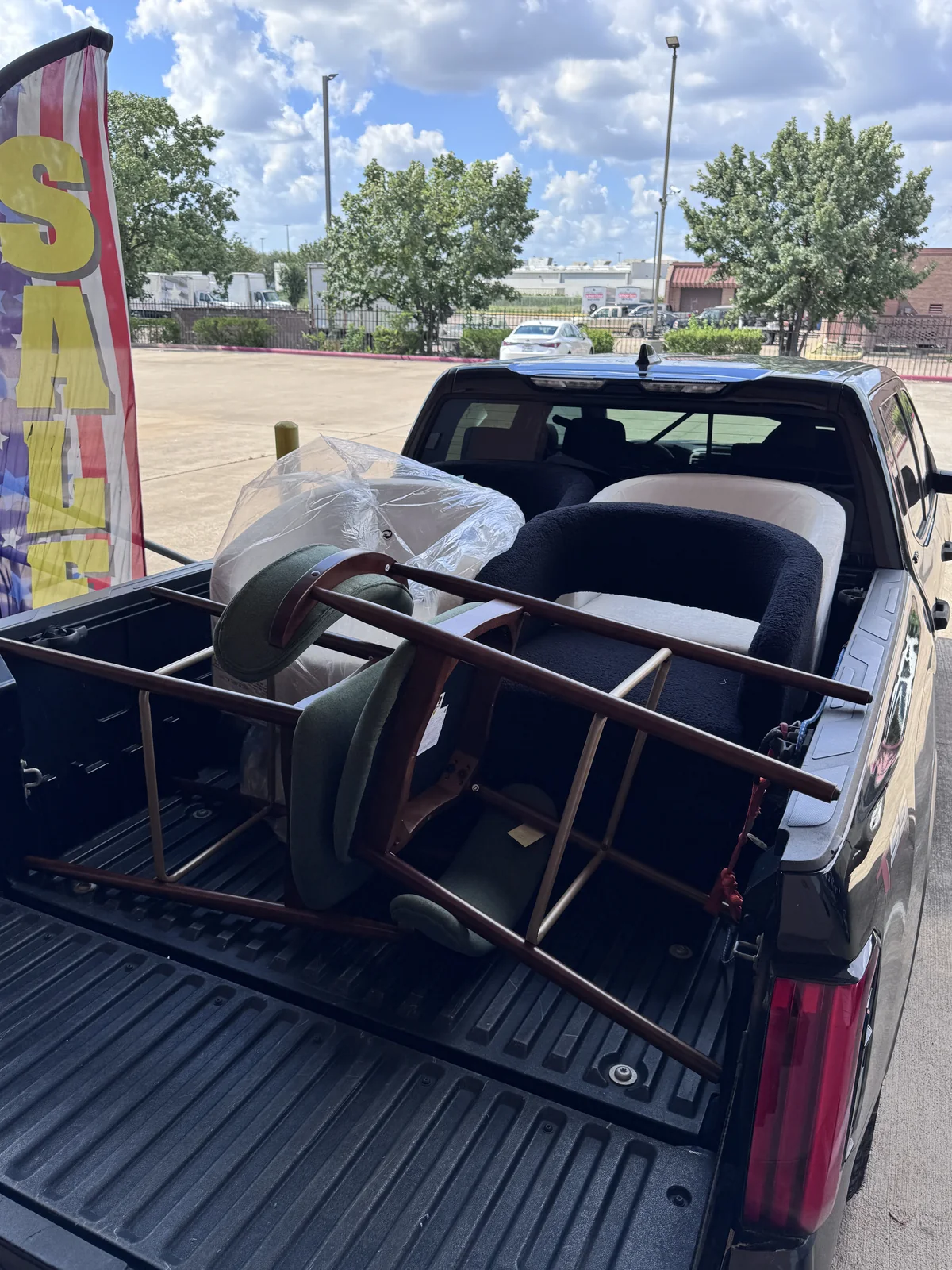 Pickup truck bed loaded with armchairs, cushions and a wrapped mattress outside the Cube-Age Houston warehouse