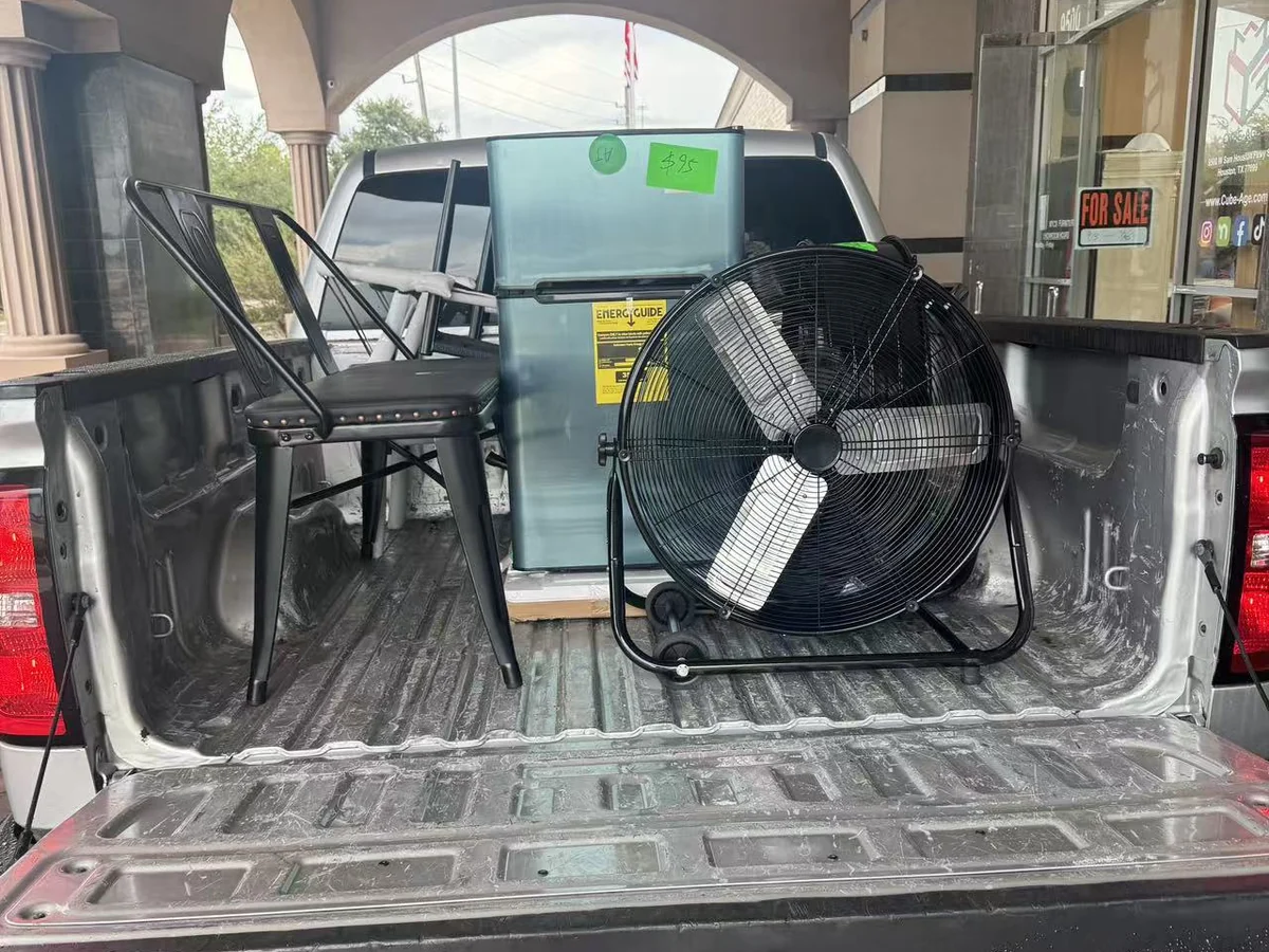 A folding table, chairs and a floor fan loaded into a customer pickup at the Cube-Age Houston sale
