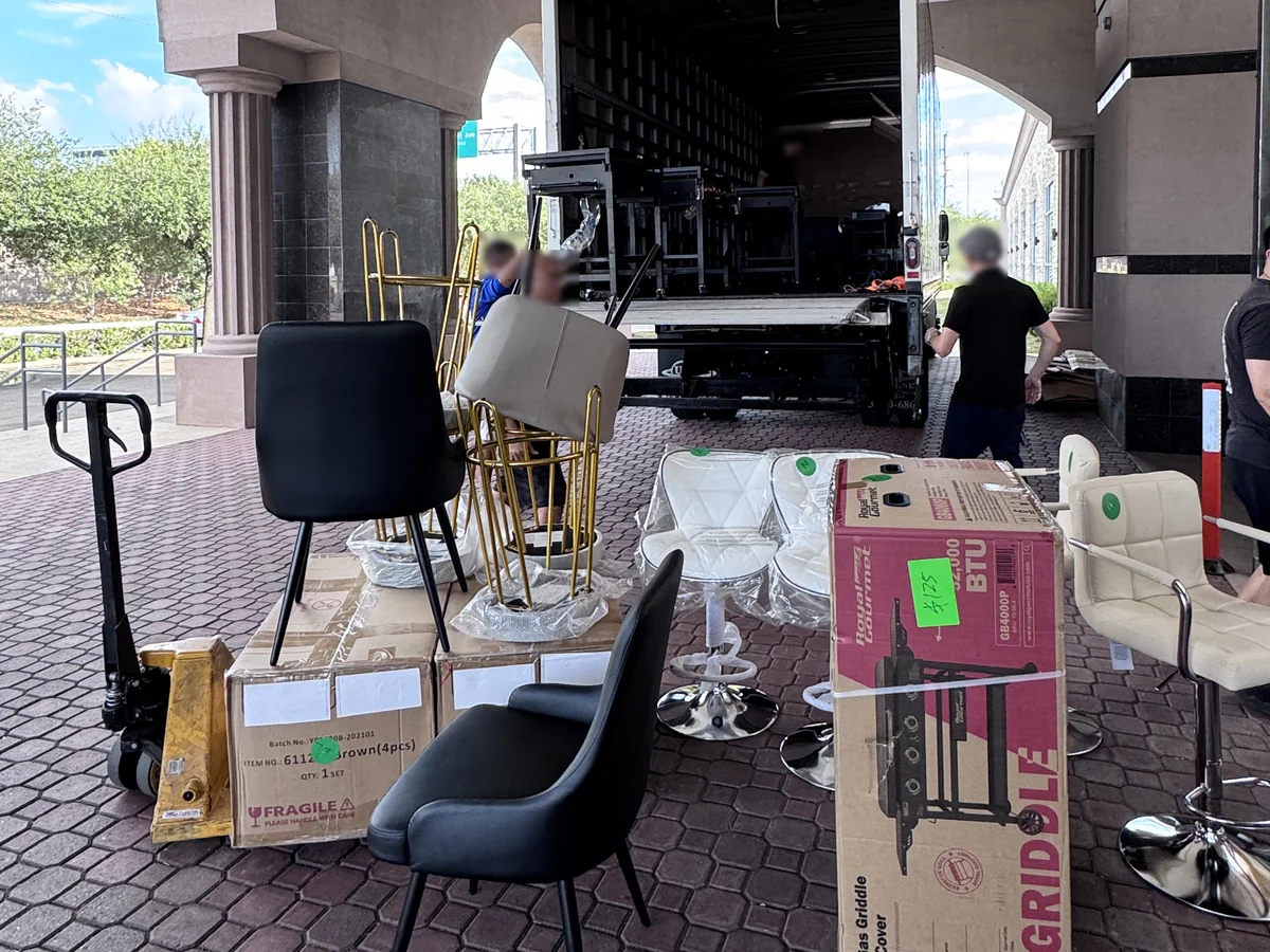 Staff loading chairs and boxed goods into a box truck at the entrance of the Cube-Age Houston sale
