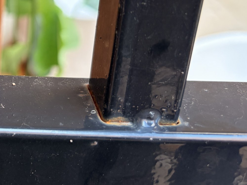Rust bleeding from the joints where pickets pass through the rail on a powder-coated steel fence panel