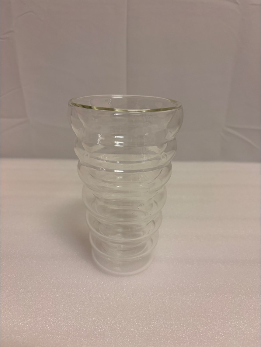 A ribbed double-wall glass cup on a white cloth