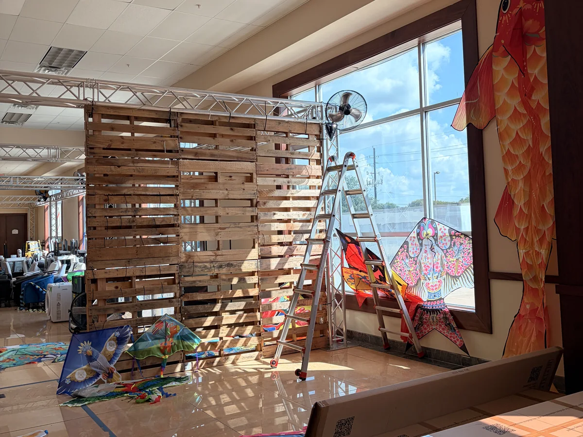 A pallet wall being built next to a window hung with kites in the Cube-Age showroom